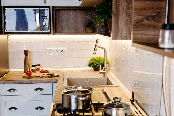 istock Modern Kitchen design in scandinavian style. stylish light grey kitchen interior with modern furniture and stainless steel appliances. wooden countertop, steel stove, board,knife and spices 1009383860