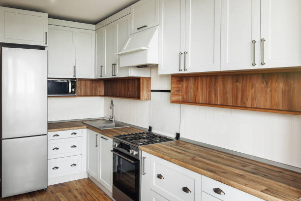 istock Stylish light gray kitchen interior with modern cabinets and stainless steel appliances. kitchen design in scandinavian style. hardwood floor and wooden worktop, granite sink and stylish faucet 1009384166