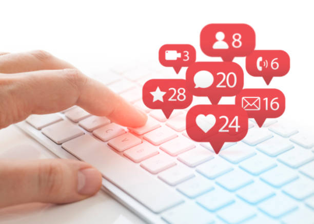 man typing on keyboard and notification icons of social network flying over keyboard stock photo