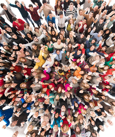 High angle view of large happy group of people standing with their hands raised and looking at camera.