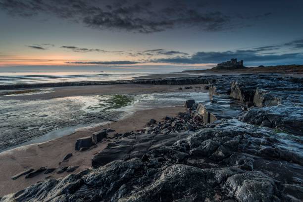 amanecer en el castillo de bamburgh - bamburgh northumberland england beach cloud fotografías e im�ágenes de stock