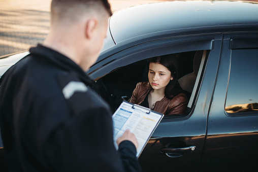 Policía en uniforme escribe multa a conductor femenino photo