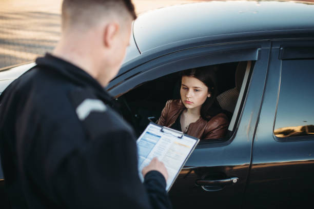 policía en uniforme escribe multa a conductor femenino - carné de conducir fotos fotografías e imágenes de stock
