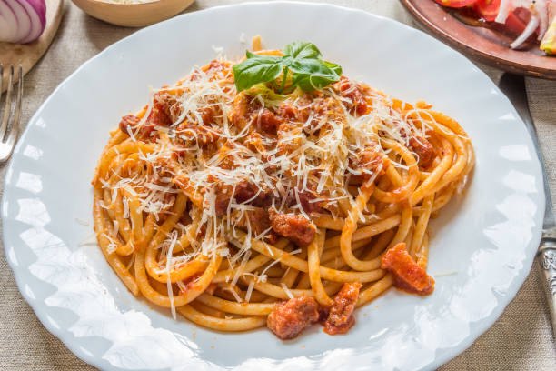 istock Pasta Amatratciana with Parmesan cheese and a basil leaf on a white plate 1009427948