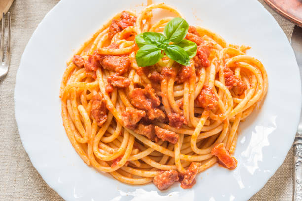 istock Pasta Amatratciana with basil leaf on a white plate 1009428004