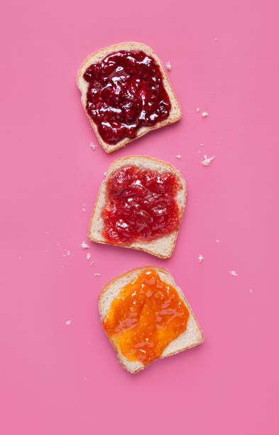 Toast slices with fruit jam on a pink background viewed from above. Selection of bread slices with fruit marmalade. Top view stock photo