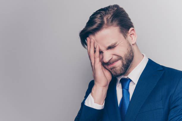 retrato de hombre decepcionado, molesto con rastrojo en traje azul, cubre medio rostro con la palma, aislado en fondo gris, olvidar algo importante que hacer, emoción tras el divorcio, la falta - embarrassment men business guilt fotografías e imágenes de stock