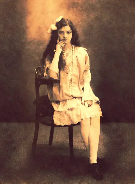 Vintage sepia toned photo of a young girl from the beginning of the twentieth century  sitting  indoors.