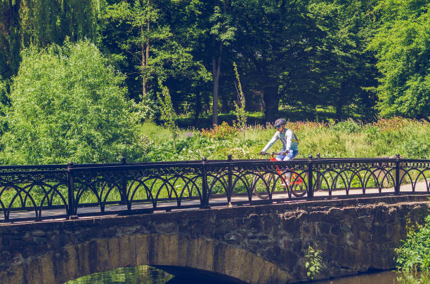 istock Cyclist in helmet riding in park on bridge 1009436366