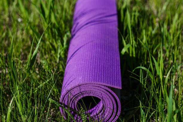 istock rolled-up yoga Mat rests on green grass 1009445244