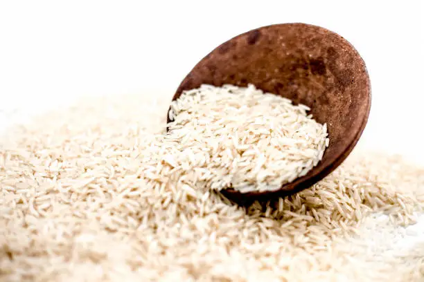 Photo of Indian special most popular uncooked Basmati long grained with a unique aroma in a clay bowl isolated on white.