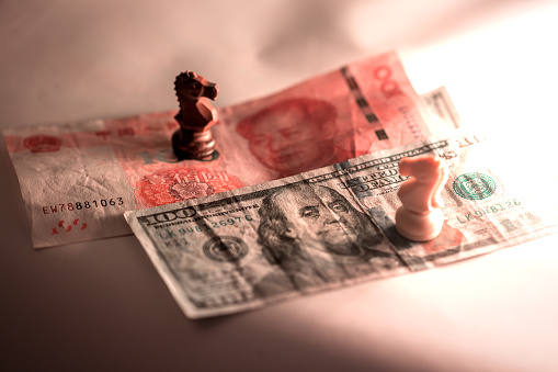 US dollar with Chinese yuan together and knight chess piece under low light