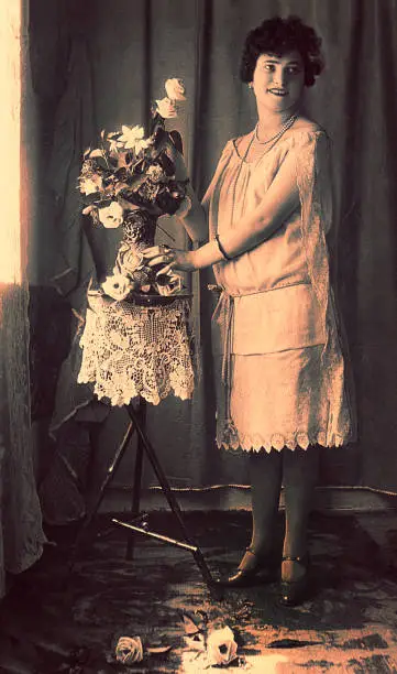 Vintage black and white photo of a young woman with a vase of flowers.