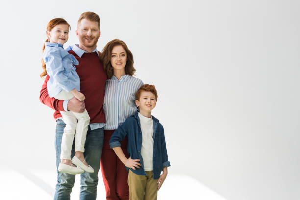 istock happy redhead family with two children smiling at camera on grey 1009456822