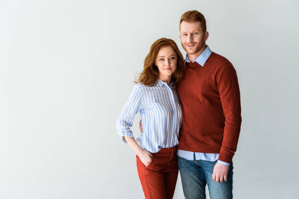 istock happy red haired couple standing together and smiling at camera isolated on grey 1009456854