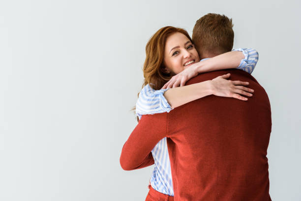 istock happy young couple hugging isolated on grey 1009456882