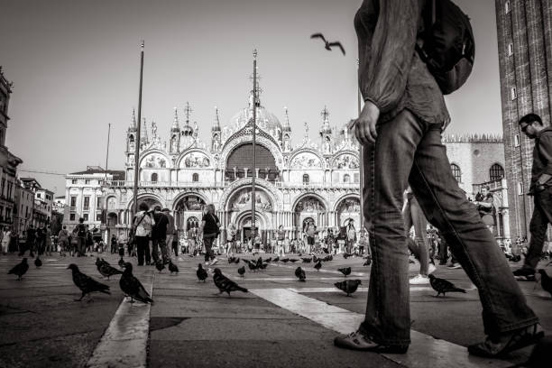 Venice, Italy - September 25, 2005: people enjoy the San Marco square in venice with many dowes at the floor waiting for being feeded.