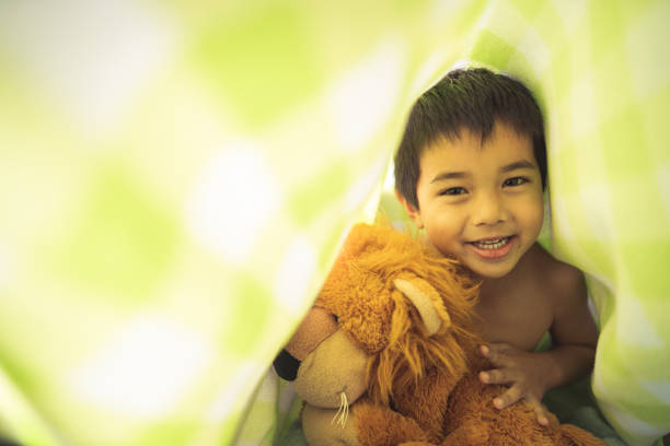 Kid in playful mood hiding under blanket.