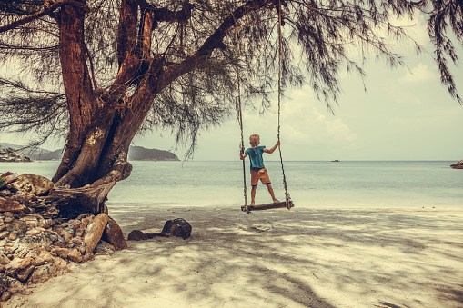 Boy  swinging on a tropical beach