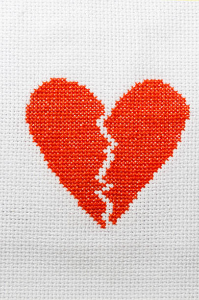 istock The broken heart is embroidered with red threads on a white cloth. 1009468726