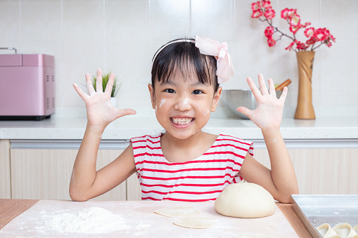Asian Chinese little girl making dumpling in the kitchen at home
