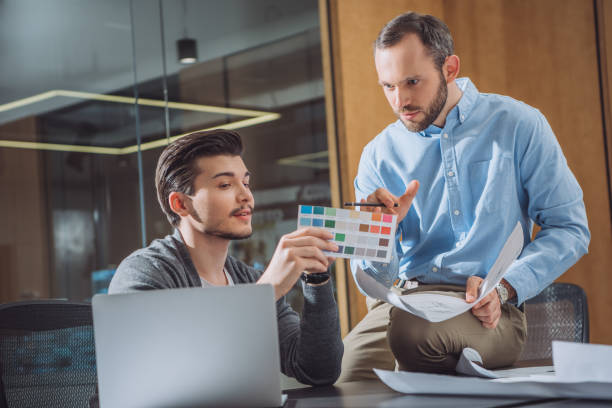 istock creative designers picking color from palette together at office 1009474318