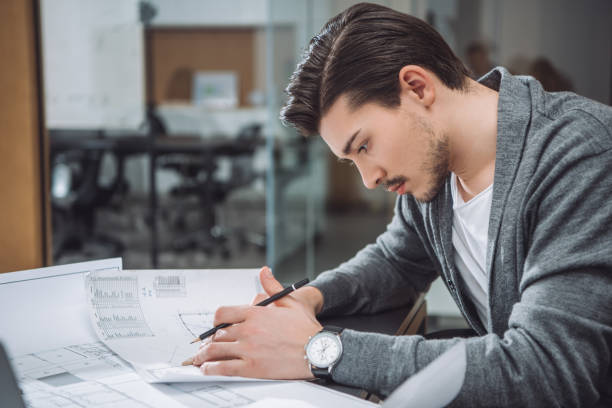istock handsome young architect drawing building plans at office 1009474490