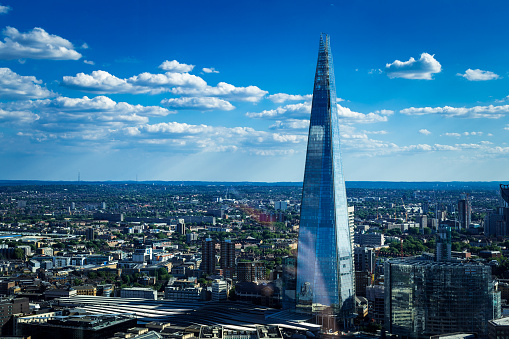 Color image depicting the modern city skyline of London, UK. Image was taken on a summer day, and includes a blue sky and cloudscape, along with lots of room for copy space.