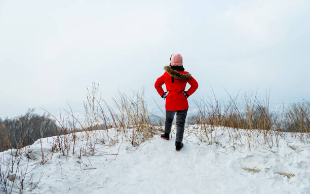 Woman standing on mountain peak with arms akimbo.