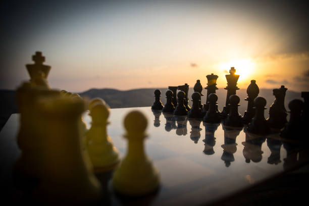 istock chess board game concept of business ideas and competition and strategy ideas. Chess figures on a chessboard outdoor sunset background. 1009487266