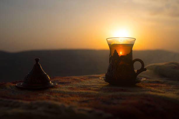 istock Arabian tea in glass on a eastern carpet. Eastern tea concept. Armudu traditional cup. Sunset background. Selective focus 1009487328