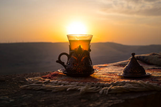 istock Arabian tea in glass on a eastern carpet. Eastern tea concept. Armudu traditional cup. Sunset background. Selective focus 1009487390