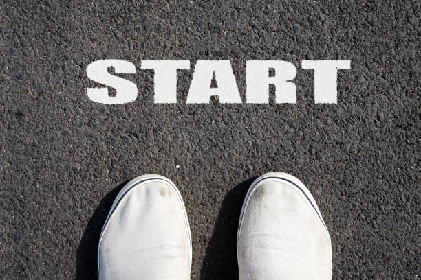 istock Two white sneakers on black asphalt. The inscription START. View from above. Copy space. 1009489922