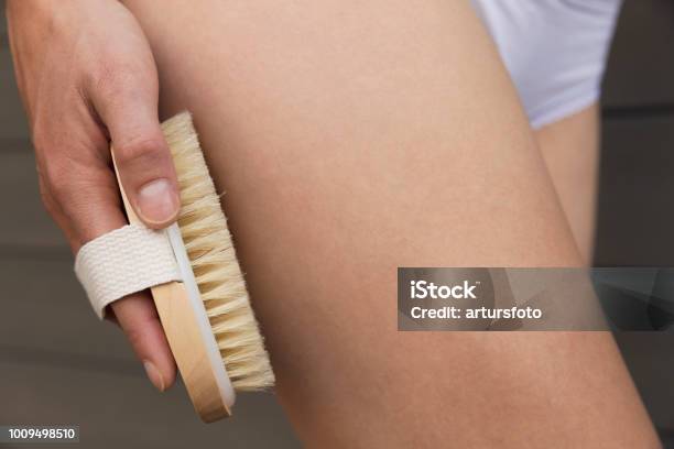 Womans Arm Holding Dry Brush To Top Of Her Leg Cellulite Treatment Dry Brushing Stock Photo - Download Image Now