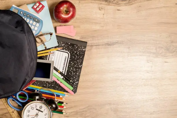 Photo of Back to school supplies on wooden student desk.