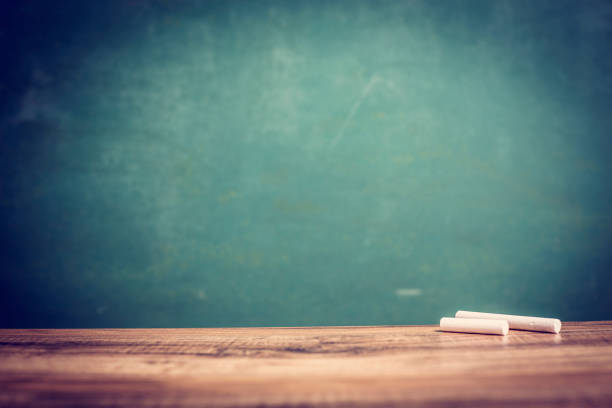 istock White chalk on wooden school desk with chalkboard. 1009498566