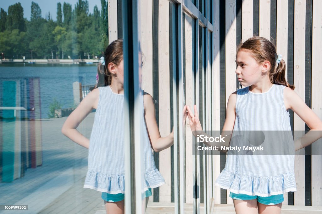 small cute girl looks at her reflection sunny day small cute girl looks at her reflection sunny day. Child Stock Photo