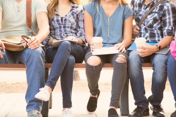 istock College student friends sitting on university campus bench. 1009499852
