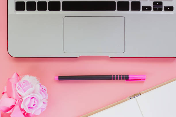 istock Computer laptop with a pen, an opened notebook and flower bouquet on pink color background for workspace concept. Flat lay and top view image. 1009512836