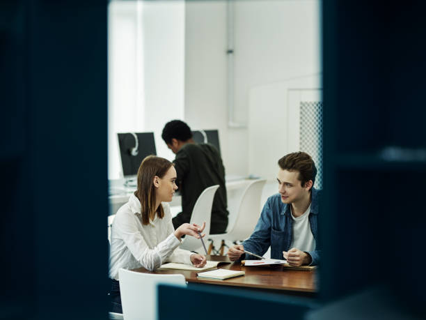 istock Young cheerful couple talking in library 1009515788