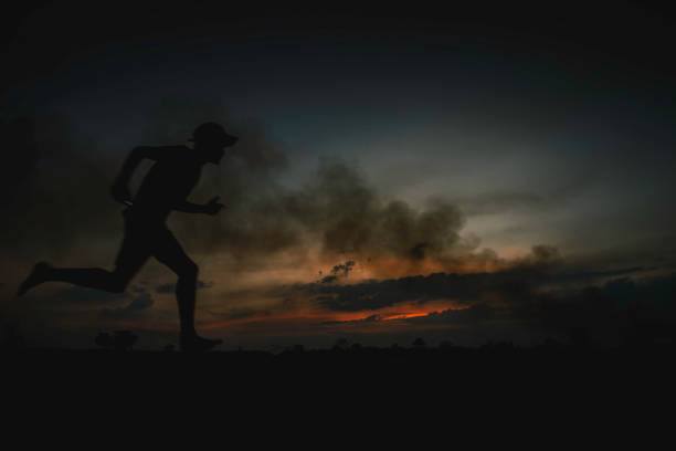 Silhouette of running man on sunset background.