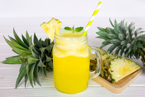 Pineapple smoothie juice yellow drink in the morning, healthy on white wood background.