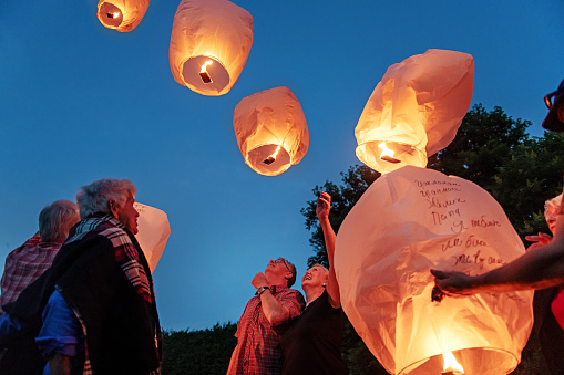 Good old friends having great times together during a summer day, making wishes and let flying chinese lantern at dusk