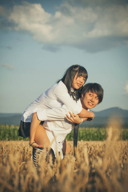 istock asian couple with school uniforms piggyback in the corn field 1009555628