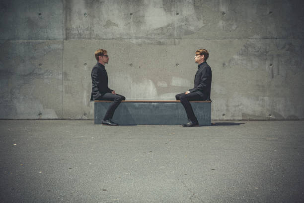 istock twin brothers sitting face to face on a bench 1009558114