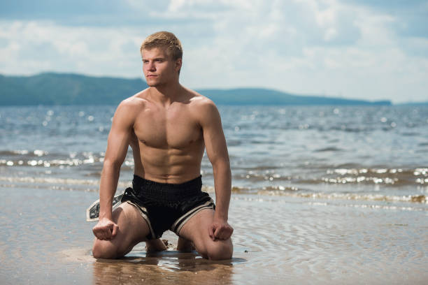 Man meditates on the beach on sea background after a workout.