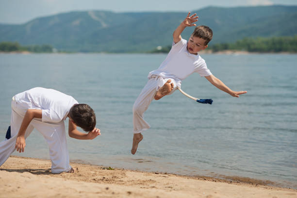 ビーチで 2 人の子供の訓練: カポエイラ、スポーツ - child sport karate education ストックフォトと画像