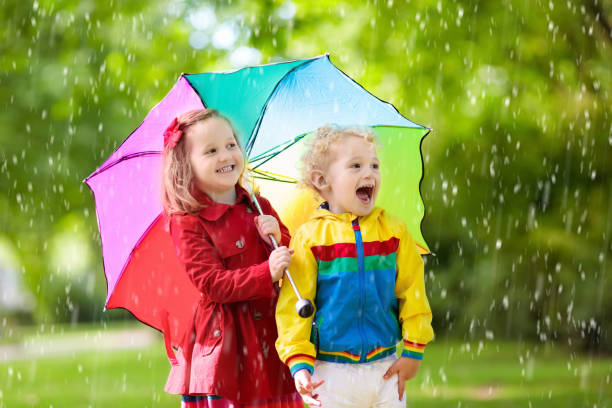 istock Kids playing in the rain under colorful umbrella 1009585016