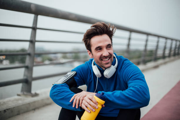istock Smiling fit man with sitting on th bridge after exercise 1009585020