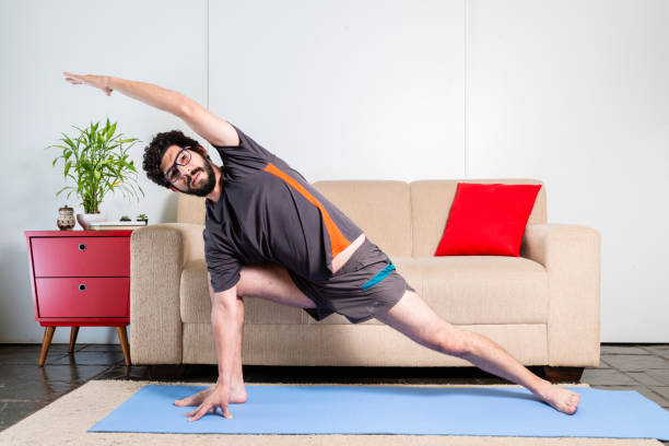 istock Beautiful caucasian bearded man in black clothes on blue yogamat doing extended side angle pose 1009592464